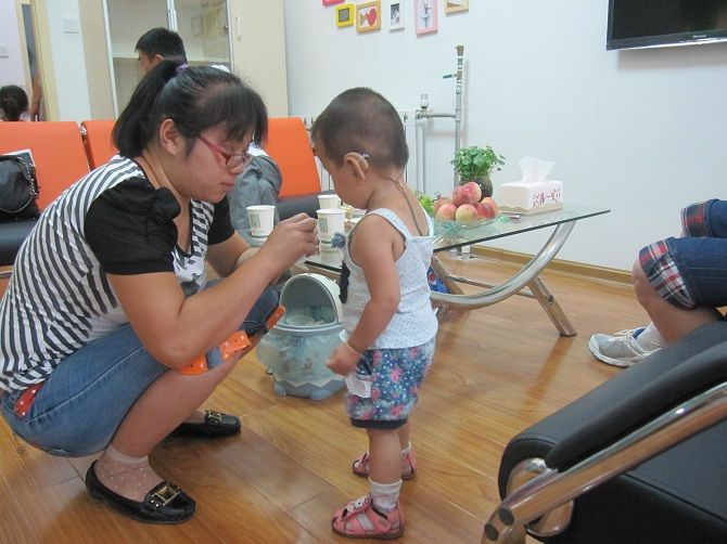 孩子家長為自己的寶寶佩戴助聽器